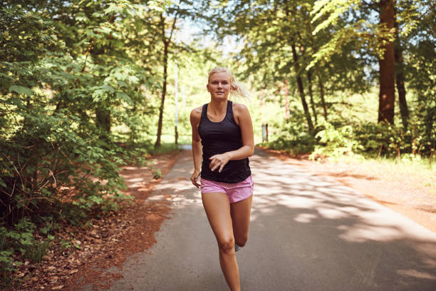 istock Fit young woman jogging alone through a forest 1009600792