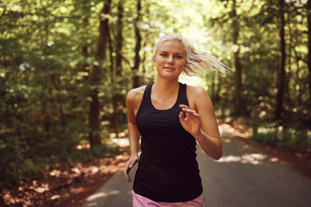 istock Smiling young blonde woman jogging alone through a forest 1009603090