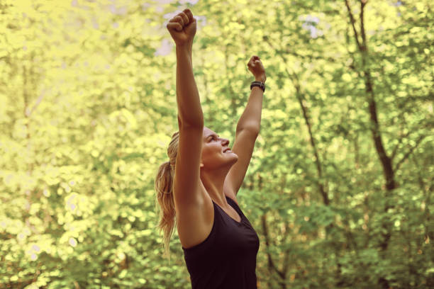 istock Woman raising her arms in triumph after a forest run 1009603374