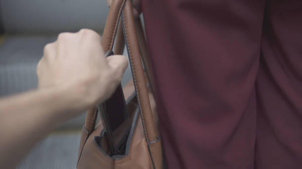 pickpocket thief is stealing smartphone from orange handbag. - woman reaching into handbag imagens e fotografias de stock