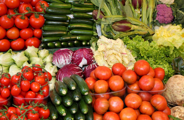 tomatoes, zucchini, artichokes and cabbages for sale on a greengrocer's stall