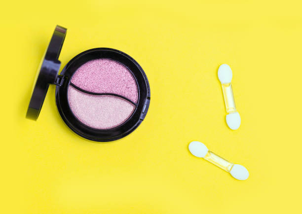 istock Pink Eye shadows and applicators on yellow background. 1009644084
