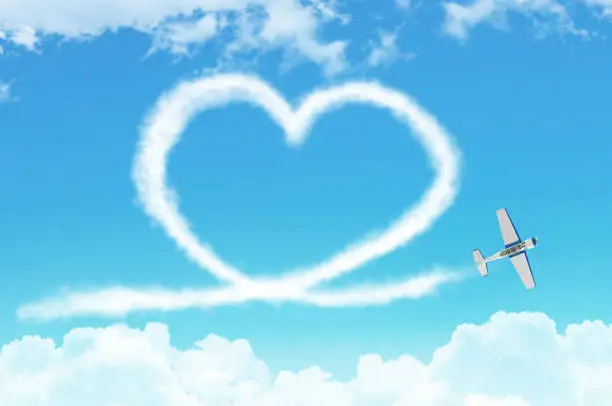Photo of Love figurative heart from a white smoke trail light-engine airplane among the clouds.