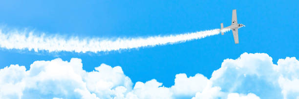 istock Light engine airplane with a trace of white smoke fly on cumulus clouds in summer, panorama. 1009644460