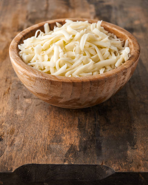 heap of grated mozzarella heap of grated mozzarella cheese in wooden bowl shredded mozzarella stock pictures, royalty-free photos & images