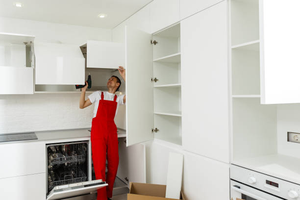 Handyman fixing kitchen s cabinet with screwdriver Handyman fixing kitchen s cabinet with screwdriver red kitchen cabinets stock pictures, royalty-free photos & images