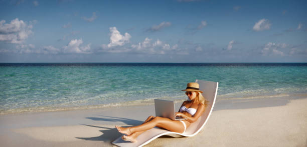 Bella giovane donna che lavora con laptop sulla spiaggia tropicale. - foto stock