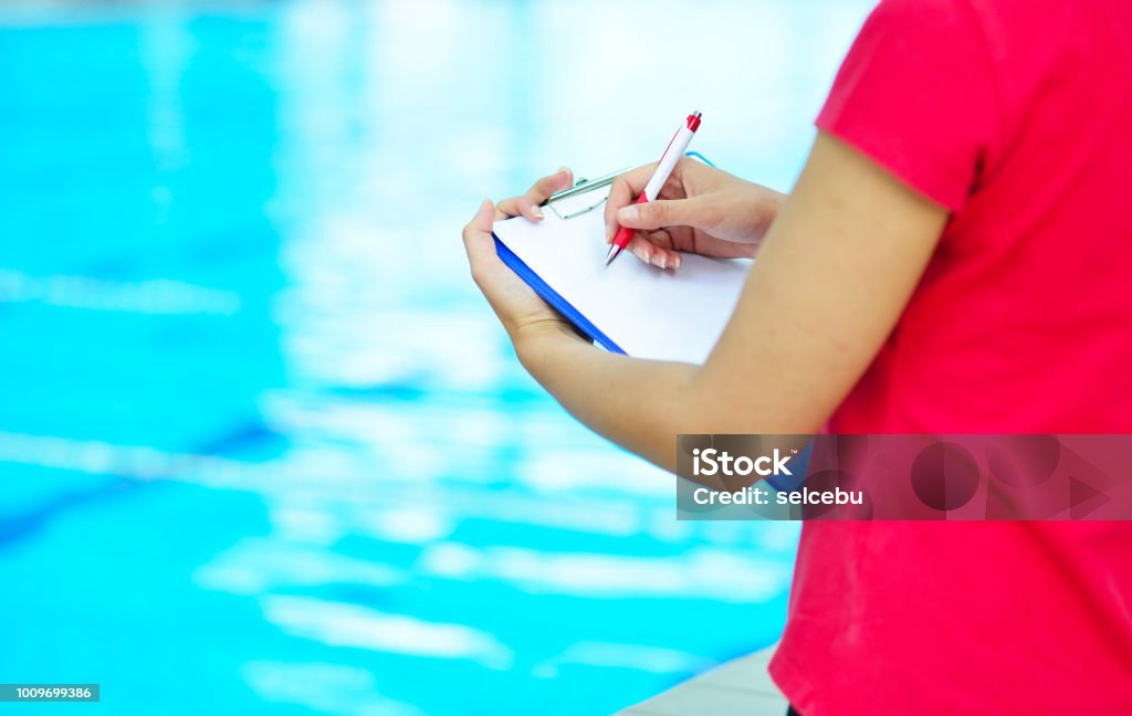 Jolie formateur en regardant le chronomètre à la piscine - Photo de Activité physique libre de droits