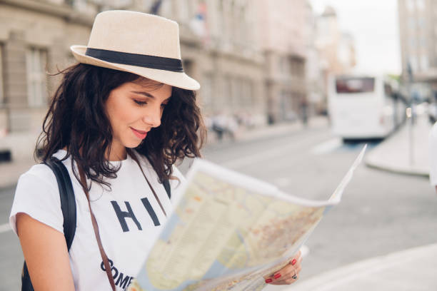 istock Young woman looking at touristic map while standing on the street 1009699796