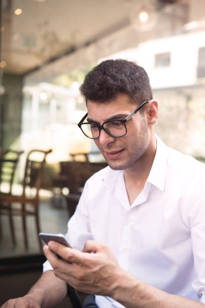 istock Young businessman working in coffee shop using smartphone. 1009702414