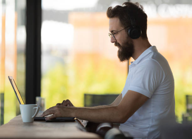 istock Young casual man using laptop in coffee shop 1009723654