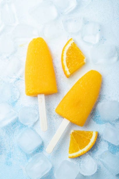 istock Orange popsicles with juice on a blue background. Ice pops, flat lay, top view 1009735892