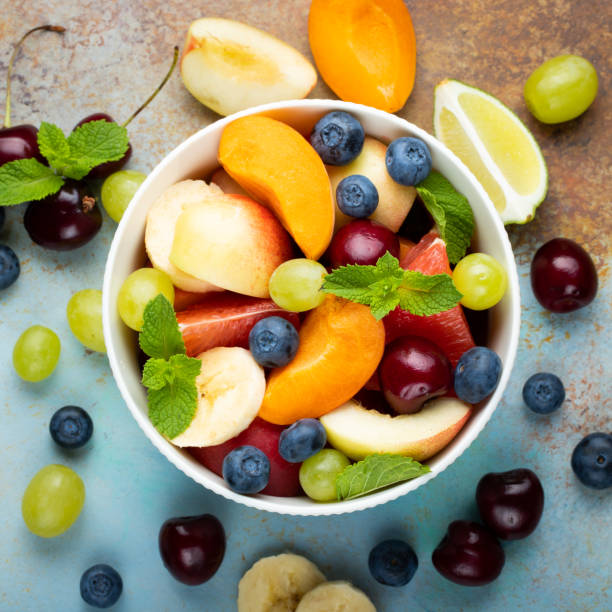 istock Bowl of healthy fresh fruit salad on a blue rusty background. Top view 1009735910