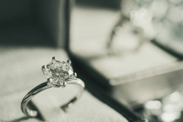 istock luxury engagement Diamond ring in jewelry gift box with bokeh light background 1009741794