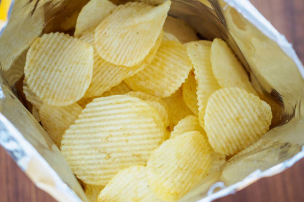 istock Potato chips in open snack bag close up on table floor 1009742346