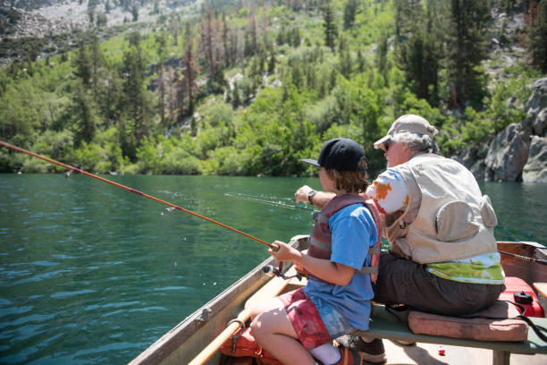 neto de professores de vovô para pescar e conduzir um barco em um lago de montanha cênica no verão. - mammoth - fotografias e filmes do acervo