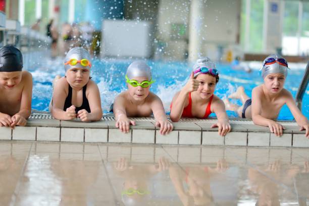 istock Happy children kids group at swimming pool class learning to swim 1009768934