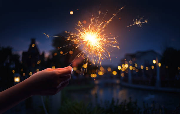 istock Hand holding a sparkler with neighborhood background 1009825400
