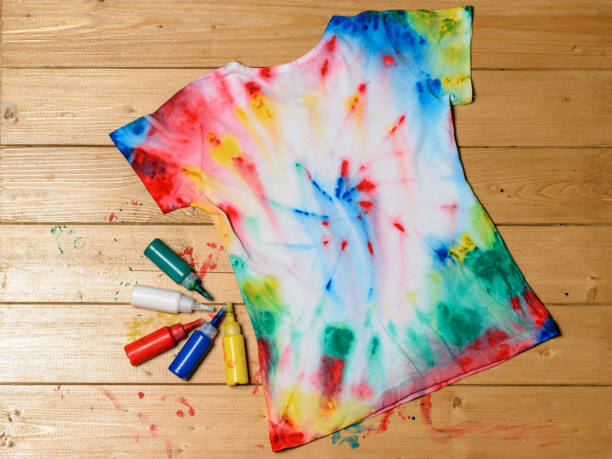 istock T-shirt painted in tie dye style on a wooden table. 1009843856
