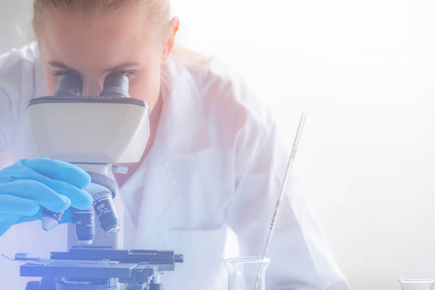 young women scientist or doctor looking through a microscope in a laboratory. young scientist doing some research,science and medical research and development concept - microscope science healthcare and medicine isolated imagens e fotografias de stock