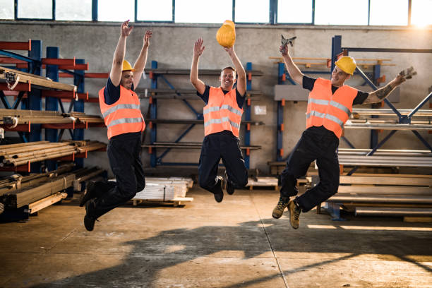 istock Happy metal workers having fun while jumping in aluminum mill. 1009864780