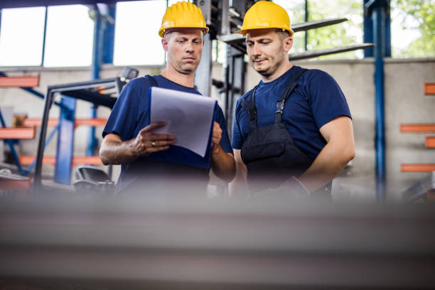 istock Below view of metal workers cooperating while going through paperwork in aluminum mill. 1009865302