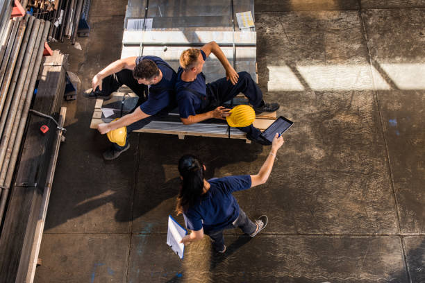 Why are you resting? You have work to do! High angle view of frustrated female manager arguing with her lazy workers in aluminum mill. lazy construction laborer stock pictures, royalty-free photos & images