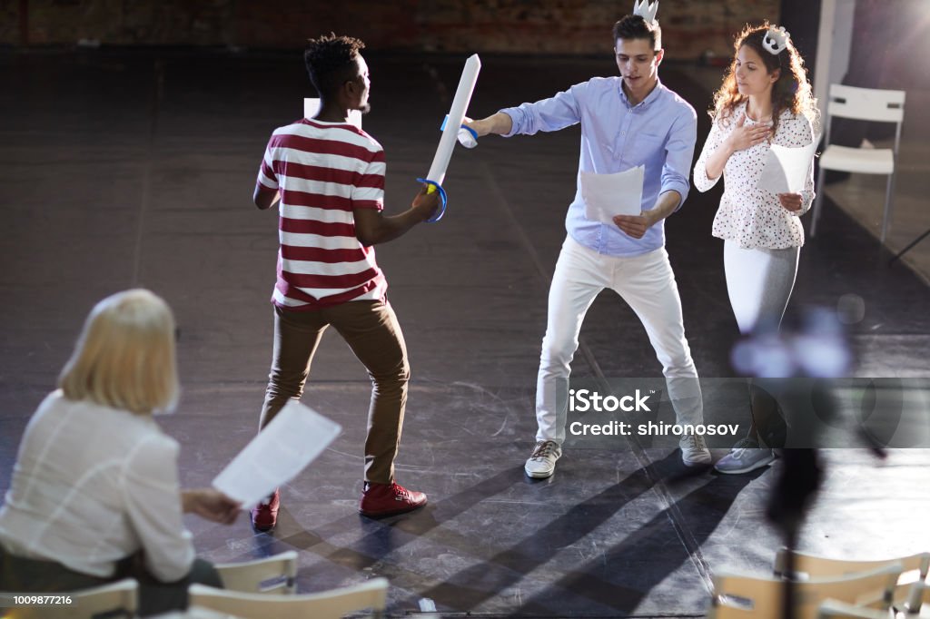 Scene of sword fighting Two young princes fighting with paper swords for heart of princess during stage repetition Theatrical Performance Stock Photo