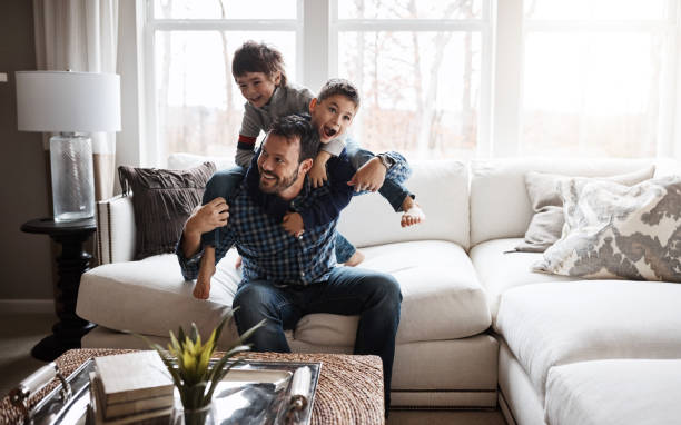 Happy kids = happy family Shot of two adorable little boys having fun with their father at home simple living photos stock pictures, royalty-free photos & images