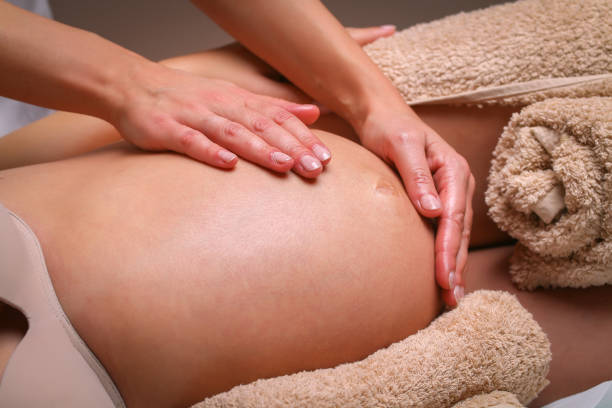 Massage therapist massaging pregnant woman stock photo