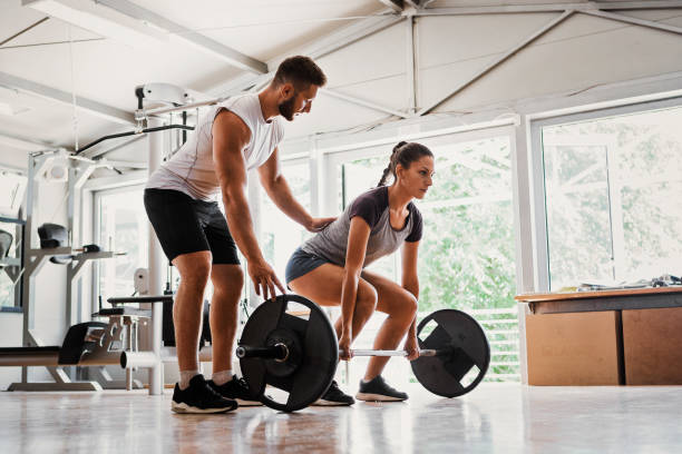 Young woman with instructor preparing for deadlift