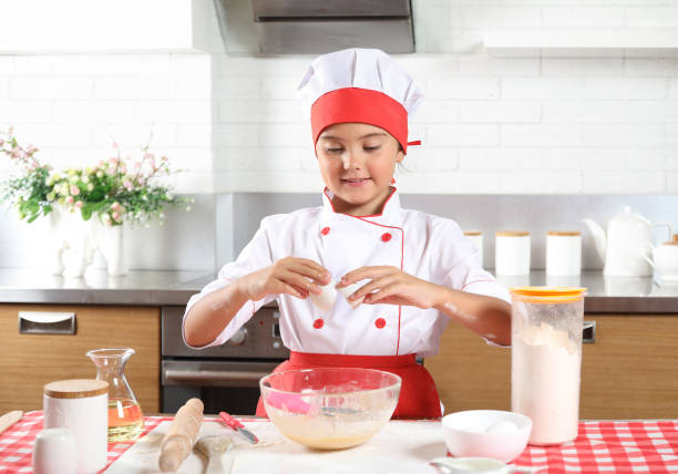 istock Little girl chef breaks an egg 1009903534