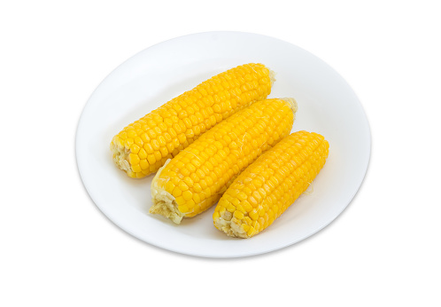 Three boiled whole ears of sweet corn on a white dish on a white background