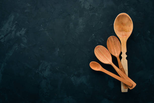 istock Wooden spoon On a black stone background. Top view. Free space for text. 1009914048