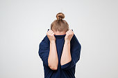 European woman hiding face under the clothes. She is oulling sweater on her head.