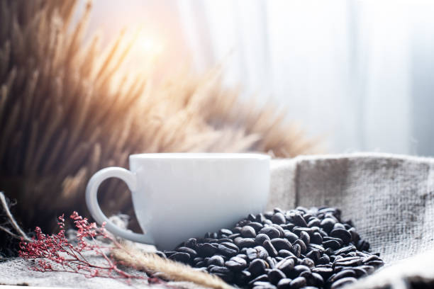 Group of coffee bean and white ceramic cup put on hemp cloth,blurry light design background