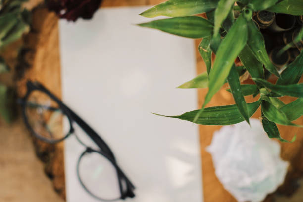 istock Blank photo frame with eyeglasses and flowers 1009943524