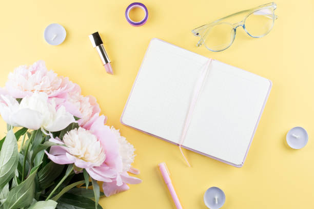 istock Flat lay home office desk. Feminine workspace with open blank note book, peony flowers, eyeglasses. 1009952252