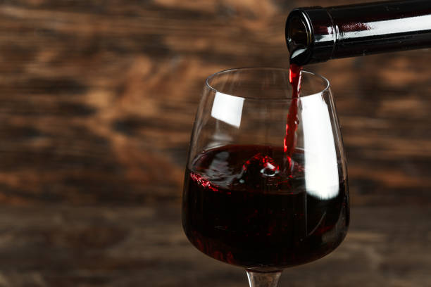 istock red wine pour into a glass on a wooden background 1009952604