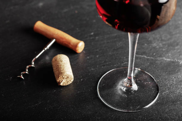 istock red wine in a glass, next to it lies a vintage corkscrew 1009952620