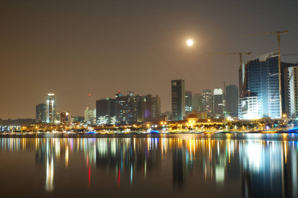 Long exposure night view of Marginal de Luanda with full moon and Mars moments before lunar eclipse stock photo