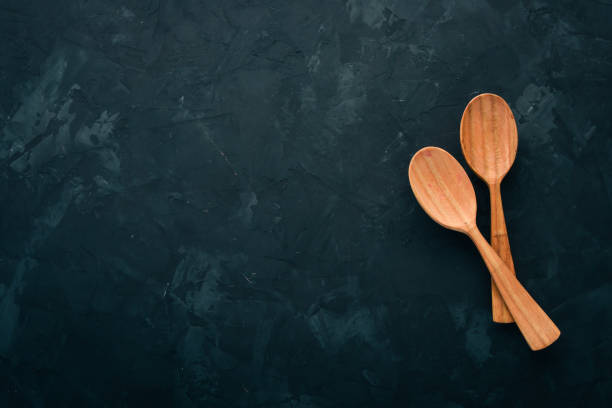 istock Wooden spoon On a black stone background. Top view. Free space for text. 1009952846