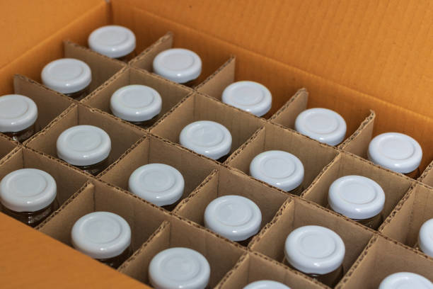 istock Glass bottles with white bottle caps in a cardboard box, Top view, Packaging concept. 1009955218