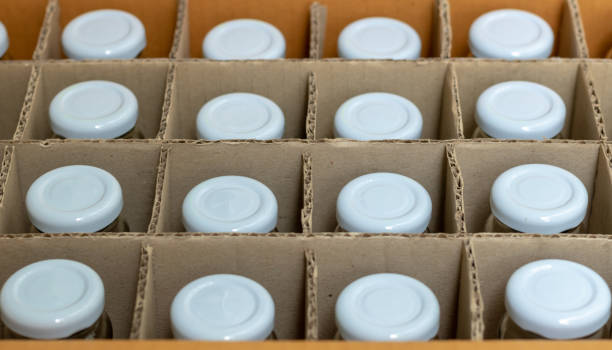 istock Glass bottles with white bottle caps in a cardboard box, Top view, Packaging concept. 1009955328