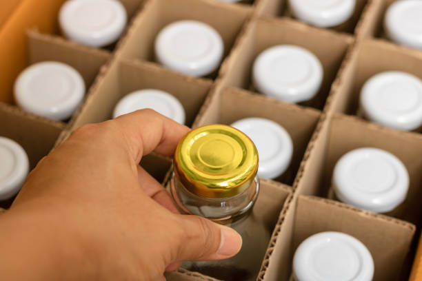 istock The hand picking a glass bottle with gold bottle caps in a cardboard box, Packaging concept. 1009955452