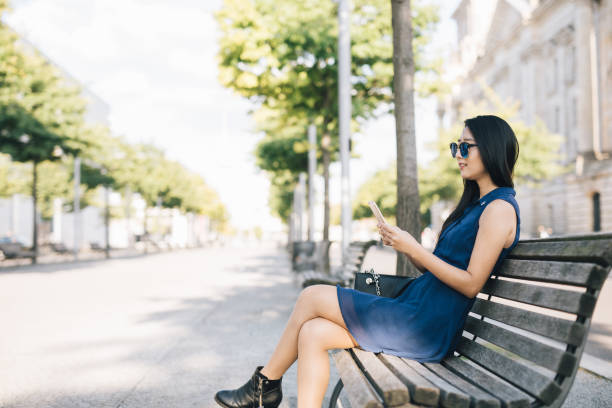 istock Woman sitting on a bench using her smartphone. 1009972918