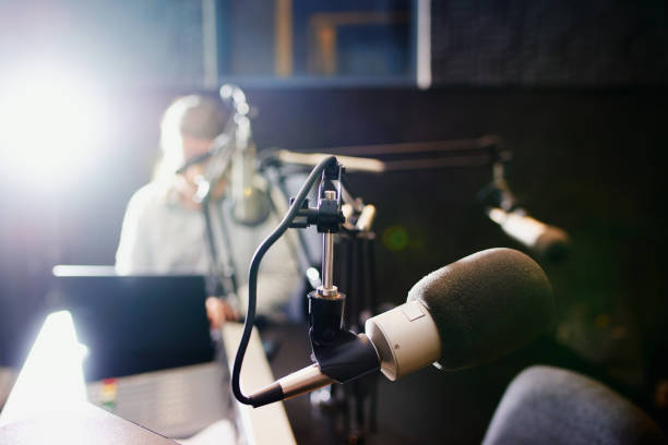 Making waves over the airwaves Shot of a microphone in a recording studio with the presenter blurred in the background radio broadcasting photos stock pictures, royalty-free photos & images