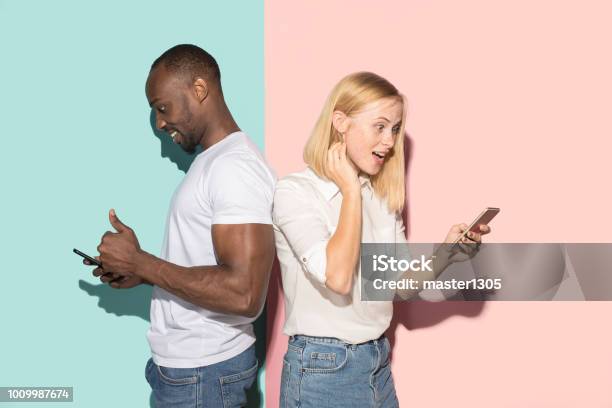 Gemischte Raste Paar Studenten Die Mobiltelefone Kaukasische Mädchen Und Ihr Afrikanischer Freund Posiert Im Studio Stockfoto und mehr Bilder von Männer