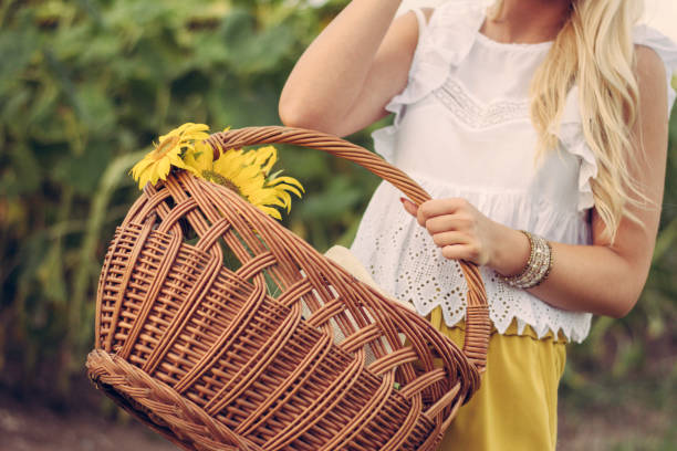 istock Woman Walking Sunflower Field With A Basket 1009996076
