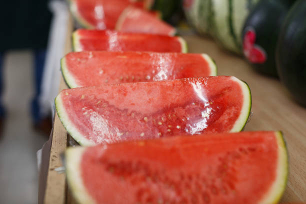 Row of ripe watermelons put up for sale on counter of fruit shop